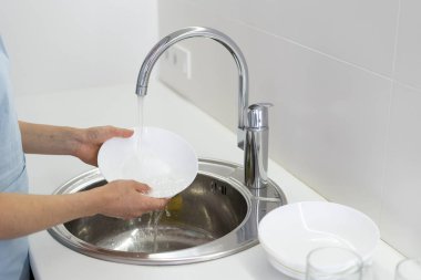 Beyaz mutfakta lavaboda kadın yıkama plakası