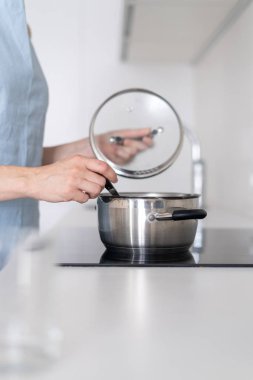 Tencerede yemek pişiren kadın, elektrikli soba içinde kullanarak