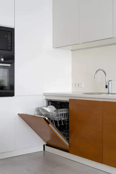 Открытая современная посудомоечная машина с тарелками и чашками на кухне — стоковое фото