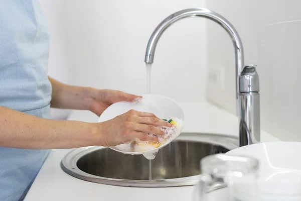 Woman using sponge with foam, washing plate in sink at white kitchen — Stock Photo, Image