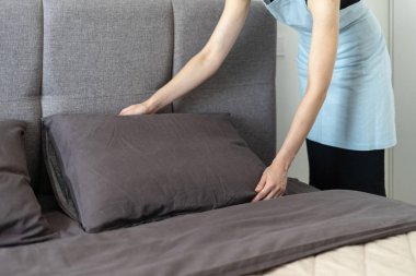 Aydınlık ve hafif yatak odası içinde yatak yapma Housemaid kadın