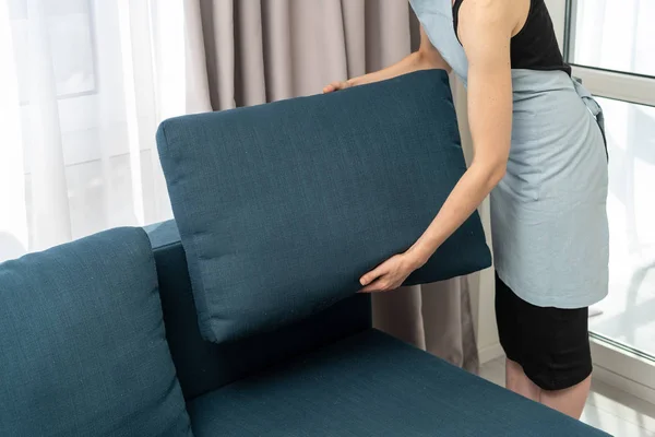 Hausmädchen mit blauem Couchkissen in der Hand — Stockfoto