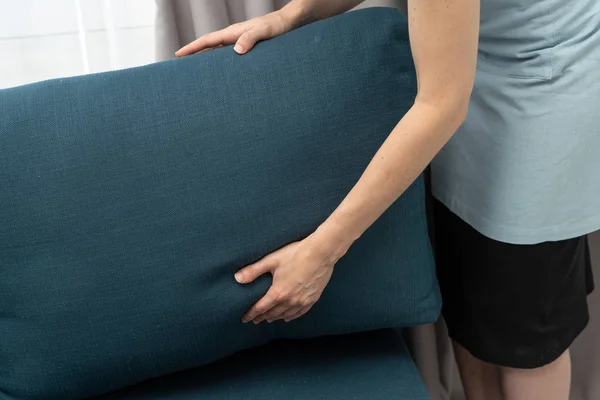 Empregada doméstica segurando travesseiro sofá azul nas mãos — Fotografia de Stock