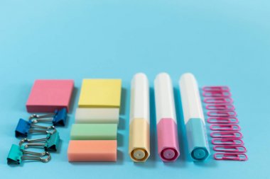 Mavi pastel arka planda kırtasiye, marker ve ataş