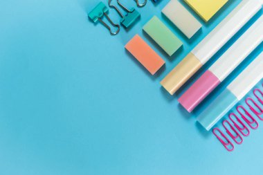 Mavi pastel arka planda kırtasiye, marker ve ataş