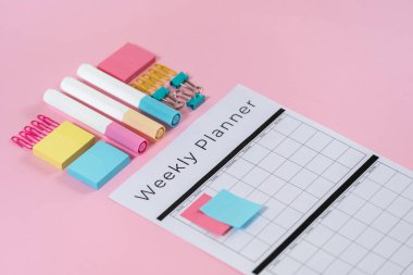 Kırtasiye ve pembe pastel arka plan üzerinde planlayıcısı