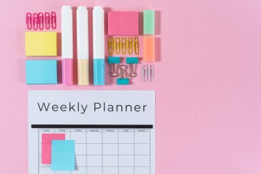 Kırtasiye ve pembe pastel arka plan üzerinde planlayıcısı