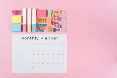 Kırtasiye ve pembe pastel arka plan üzerinde planlayıcısı