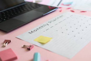 Dizüstü bilgisayar, kırtasiye ve pembe pastel arka plan üzerinde planlayıcısı