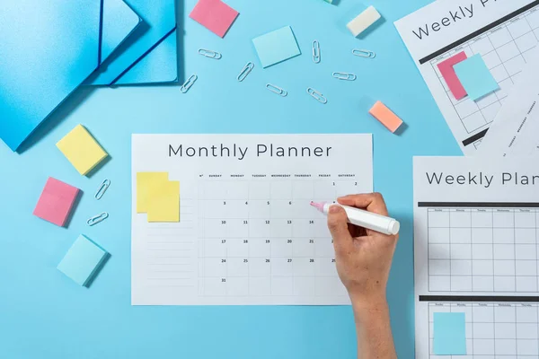 Woman writing at planner on blue pastel background — Stock Photo, Image