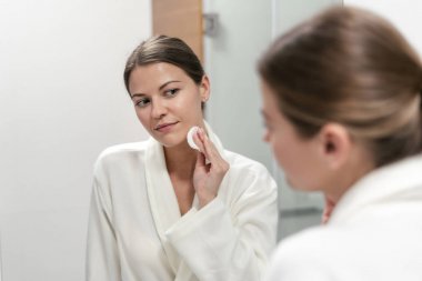 Elinde pamuk ped tutan beyaz bornozlu kadın 