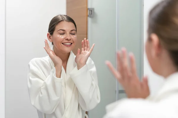 Mujer de pie en el baño con crema en la cara — Foto de Stock