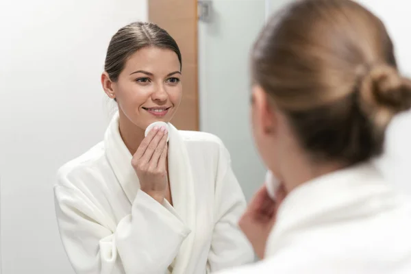 Woman in white bathrobe holding cotton pad in hands — Stock Photo, Image