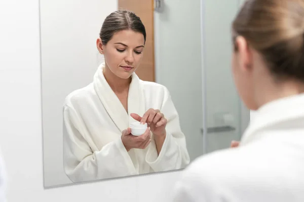 Woman holding cream in hands, standing at bathroom — Stock Photo, Image