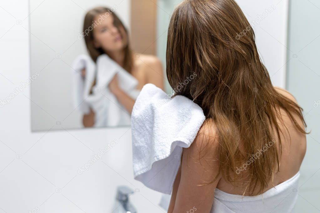 Woman wiping wet hair with towel in bathroom
