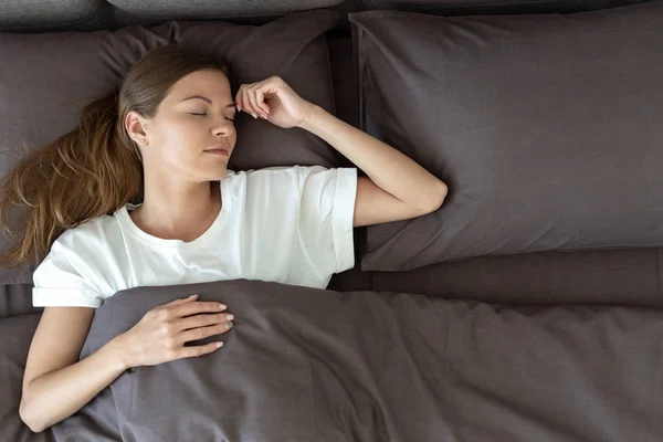 Jong volwassen vrouw slapen op bed in de ochtend — Stockfoto