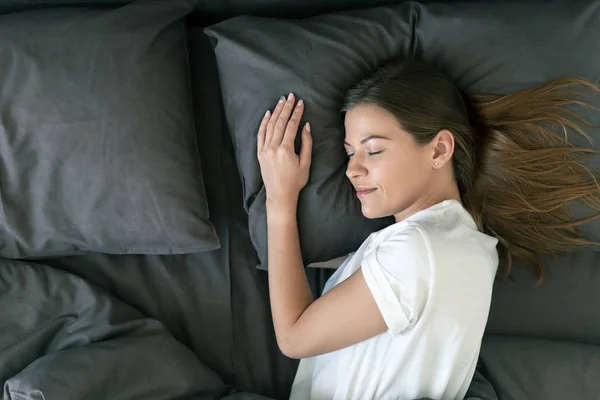 Jong volwassen vrouw slapen op bed in de ochtend — Stockfoto