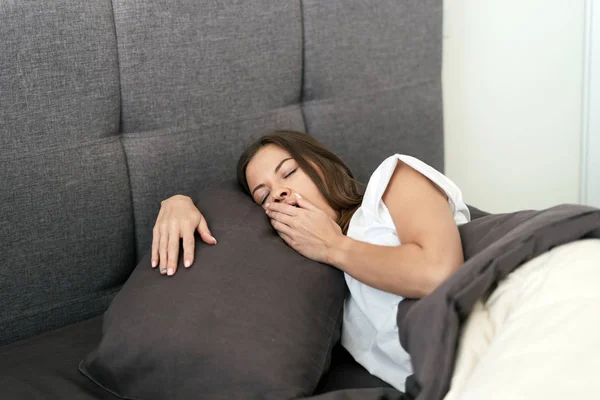 Junge erwachsene Frau schläft morgens auf dem Bett — Stockfoto