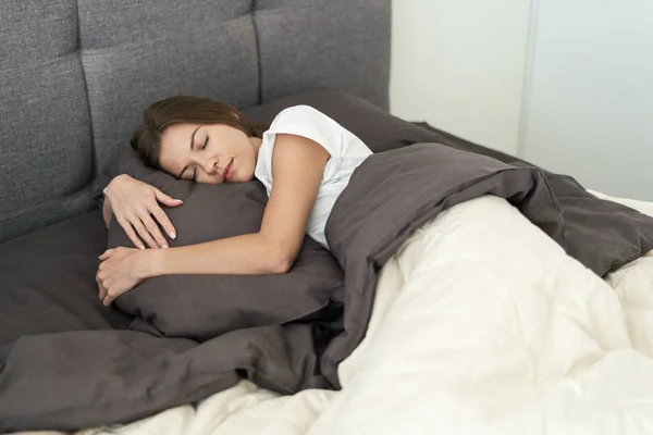 Junge erwachsene Frau schläft morgens auf dem Bett — Stockfoto