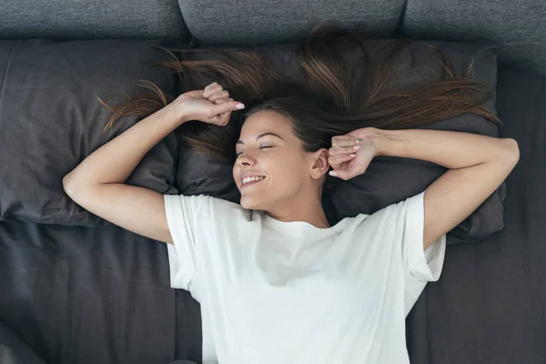 Jong volwassen vrouw awaiking op bed in de ochtend — Stockfoto