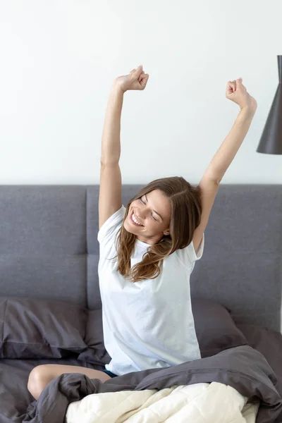 Jong volwassen vrouw awaiking op bed in de ochtend — Stockfoto