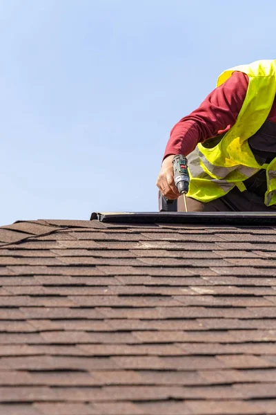 Працівник встановлює елемент черепичного даху на новий будинок під час будівництва — стокове фото