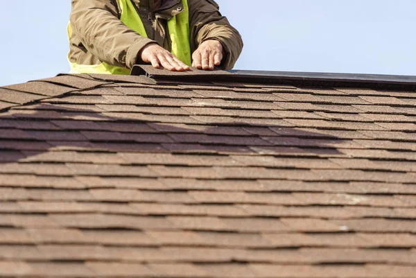 Працівник встановлює елемент черепичного даху на новий будинок під час будівництва — стокове фото