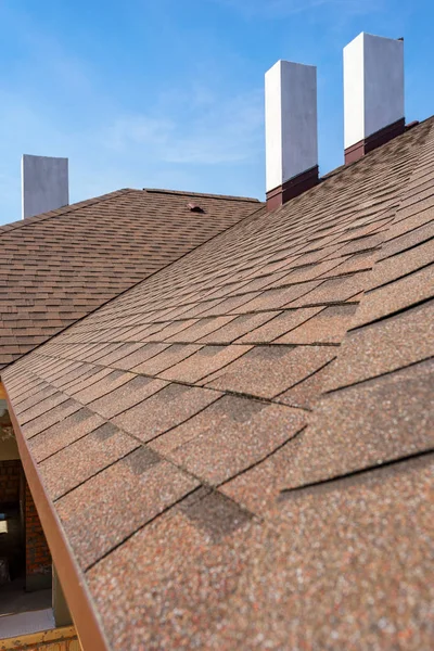 Asphalt tile roof with chimney on new home under construction