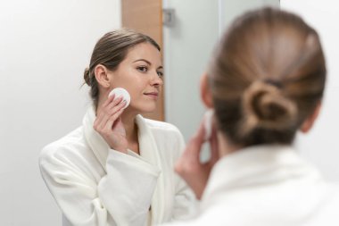 Elinde pamuk ped tutan beyaz bornozlu kadın 