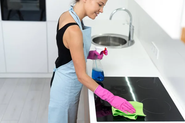 Молодая женщина чистит электрическую плиту на кухне — стоковое фото