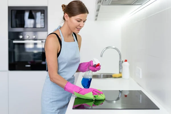 Молодая женщина чистит электрическую плиту на кухне — стоковое фото