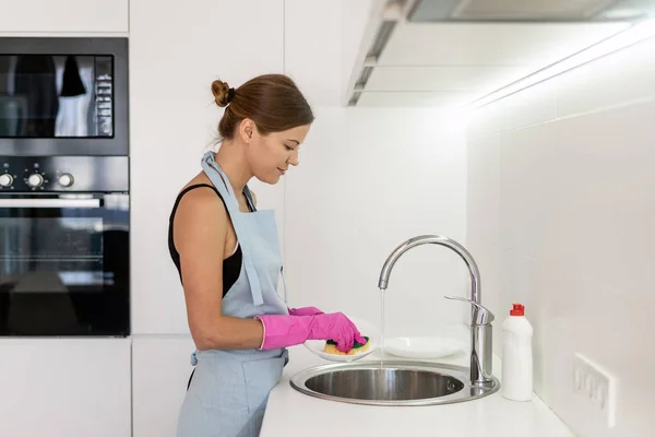 Молодая женщина моет тарелки на кухне — стоковое фото
