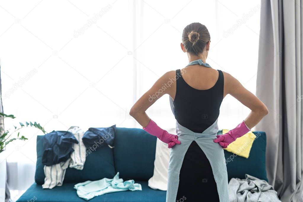 Young adult woman looking at mess on couch