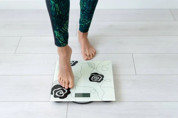 Young sporty woman standing on flooring scale weight
