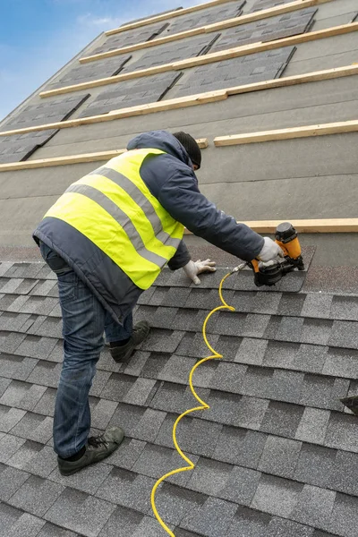 Workman using pneumatic nail gun install tile on roof of new hou — Stock Photo, Image