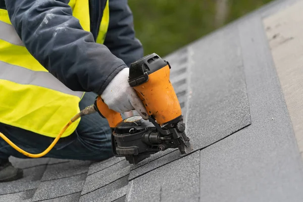 Workman met pneumatische Nagelpistool installatie tegel op dak van nieuw huis in aanbouw — Stockfoto