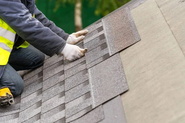 Arbeiter montieren Ziegel auf Dach des im Bau befindlichen Hauses — Stockfoto