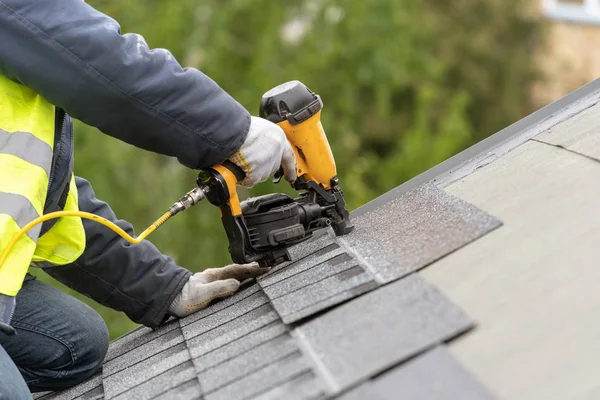 Workman using pneumatic nail gun install tile on roof of new hou — Stock Photo, Image