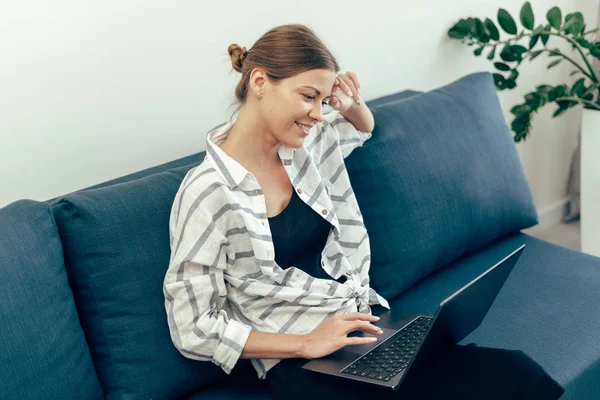 Mladá dospělá žena používající moderní laptop a usmívající se — Stock fotografie