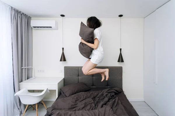 Junge erwachsene Frau wacht auf und springt auf Bett — Stockfoto