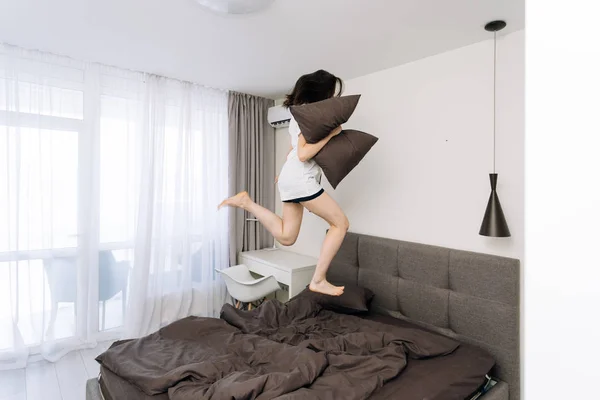 Junge erwachsene Frau wacht auf und springt auf Bett — Stockfoto