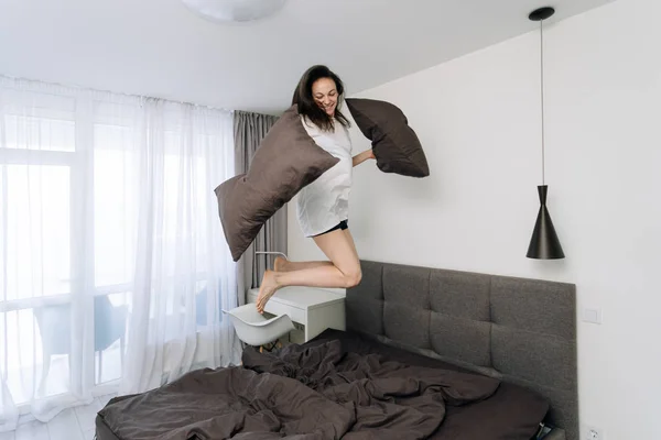 Jovem mulher adulta acordando e pulando na cama — Fotografia de Stock