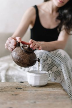 Çaydanlık tutan ve fincana çay döken kadın 