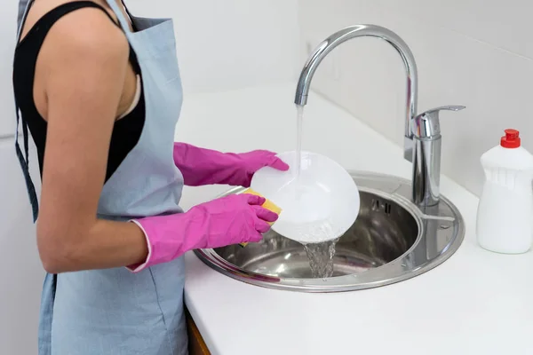 Mujer joven adulta lavando platos en la cocina — Foto de Stock