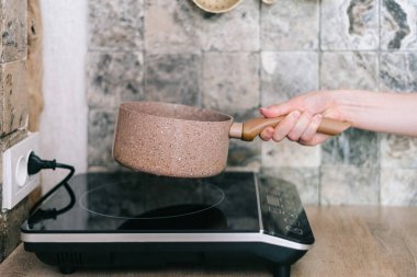 Kadın küçük elektrikli soba tava koyarak