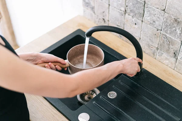 Femme tenant verser de l'eau du robinet dans la casserole — Photo