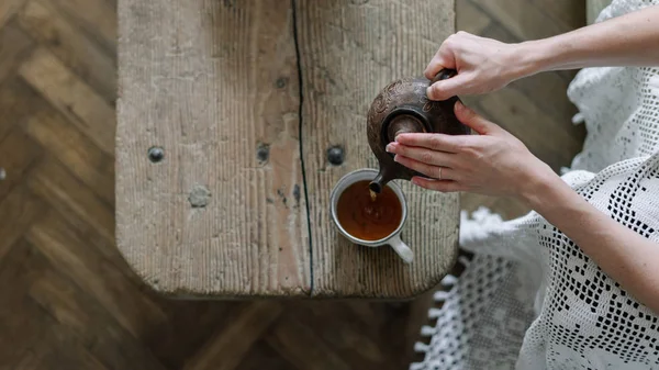Mulher segurando bule e derramando chá na xícara — Fotografia de Stock