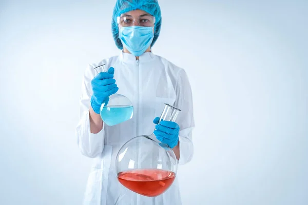 Woman holding medical glass bottle with liquid, making laborator