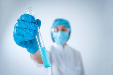 Test tüpünü sıvı ile tutan bilimsel bir kadın laboratuvar analizi yapıyor.