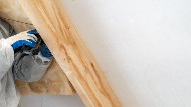 Profesyonel ustabaşı çatının altına termal yalıtım katmanı yerleştiriyor.